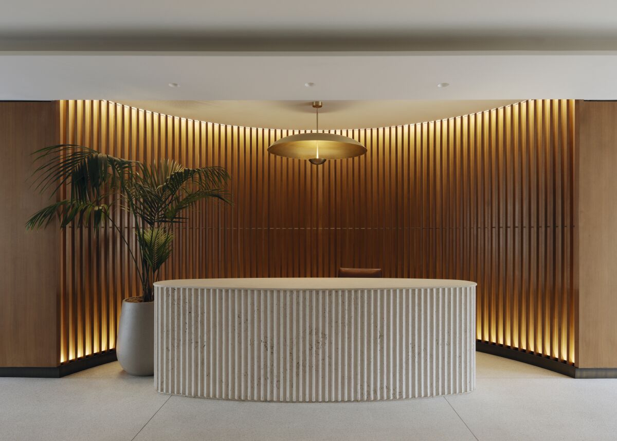 An elegant lobby centers around a rippled travertine desk which sits before a rippled wall.
