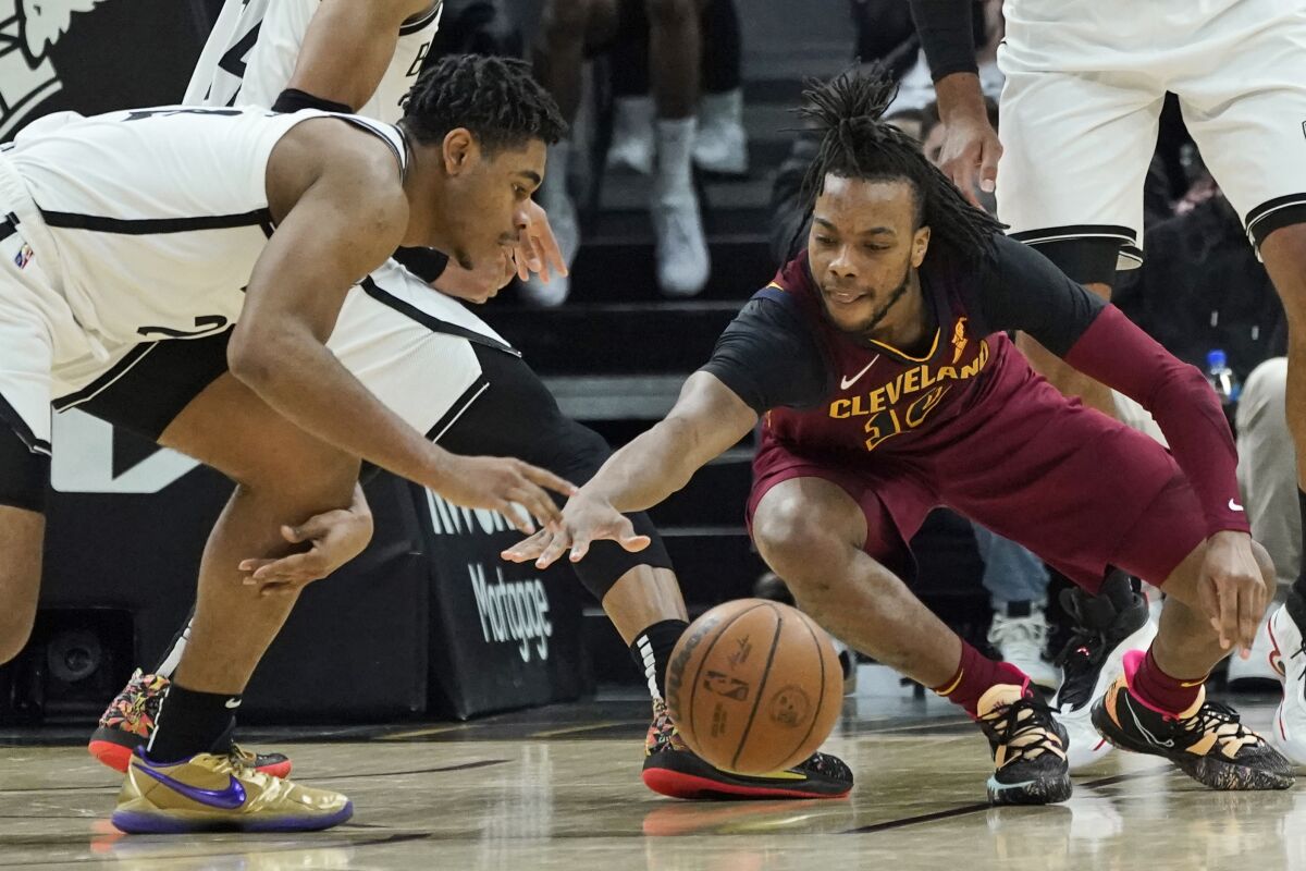 Brooklyn Nets' Cam Thomas, left, grabs the ball ahead of Cleveland Cavaliers' Darius Garland in the second half of an NBA basketball game, Monday, Jan. 17, 2022, in Cleveland. (AP Photo/Tony Dejak)