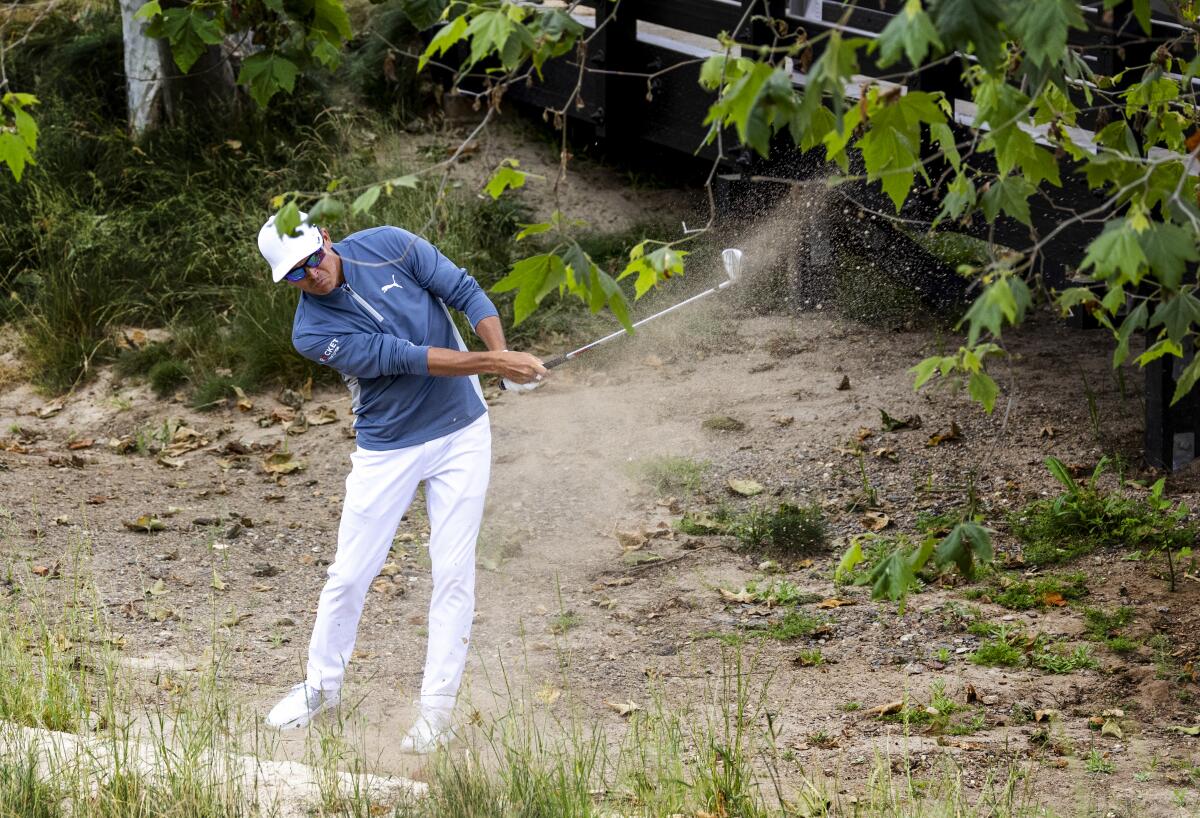 Co-leader Rickie Fowler hits out of the sandy rough on the ninth hole at the Los Angeles Country Club.
