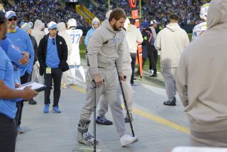 Los Angeles Chargers linebacker Joey Bosa walks with a boot and crutches on the sideline.