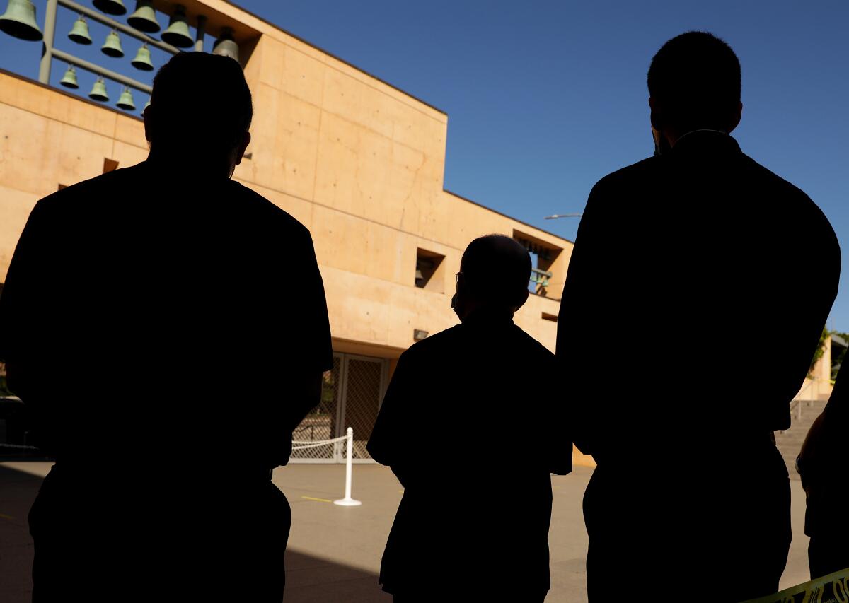 Three clergy members are silhouetted outside church