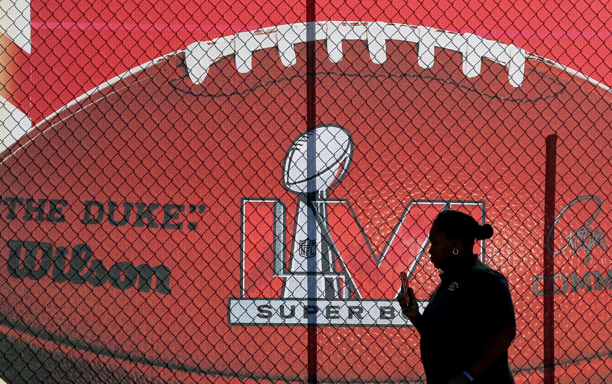 A passerby takes a selfie next to a Super Bowl LVI banner