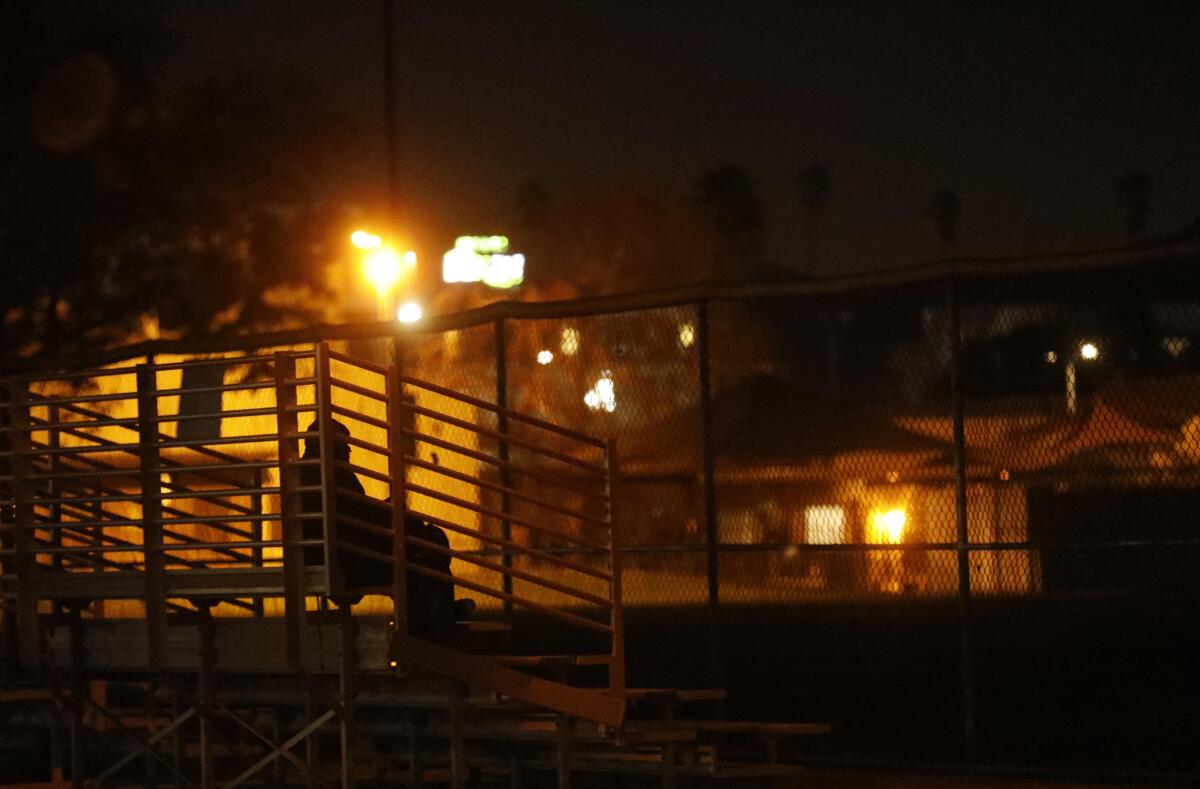 Seen from behind, a person sitting in empty bleachers at night