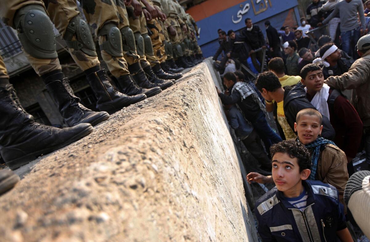 Egyptian soldiers atop a wall at Cairo’s Tahrir Square as young protesters demand on Nov. 24, 2011, that the interim military leadership step down.