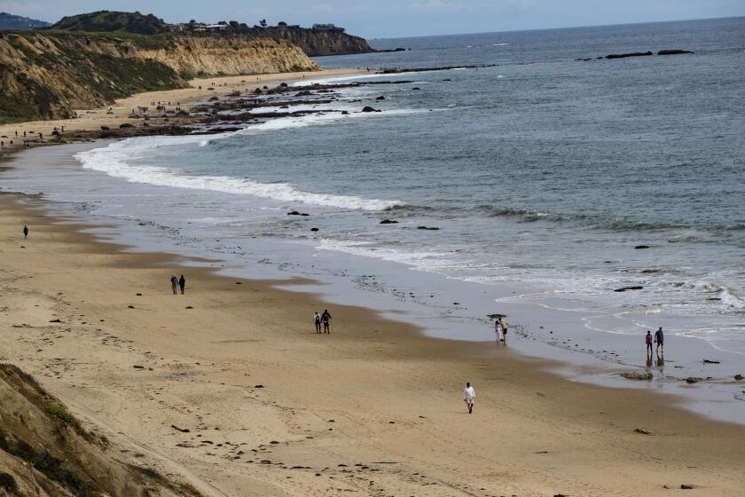 NEWPORT BEACH, CA - MARCH 20, 2020: People walk the beach, but keep "social distancing" during the coronavirus outbreak at Crystal Cove on March 20, 2020 in Newport Beach, California. (Gina Ferazzi/Los AngelesTimes)