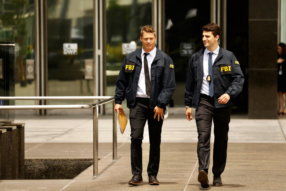 Two men in FBI jackets walk out of a building