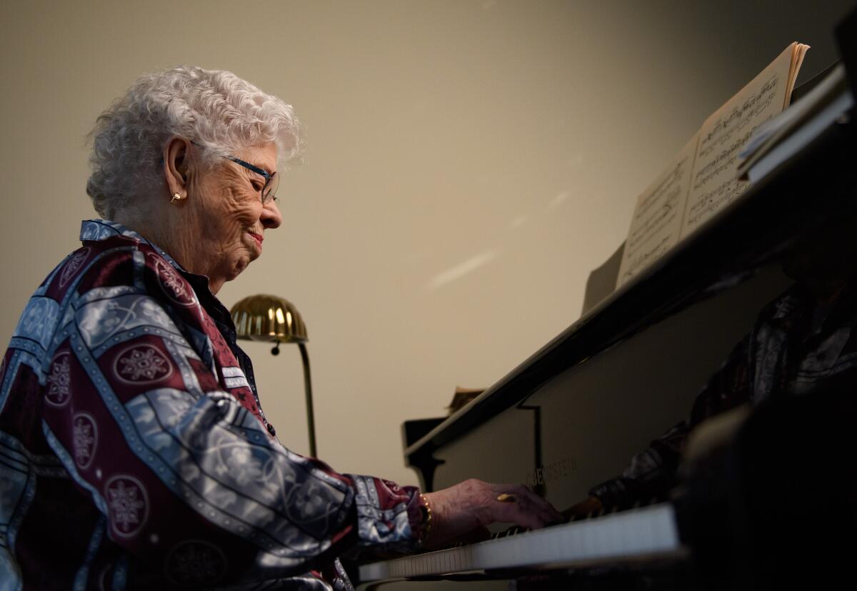 Joanne Rogers plays the piano in her Pittsburgh apartment.