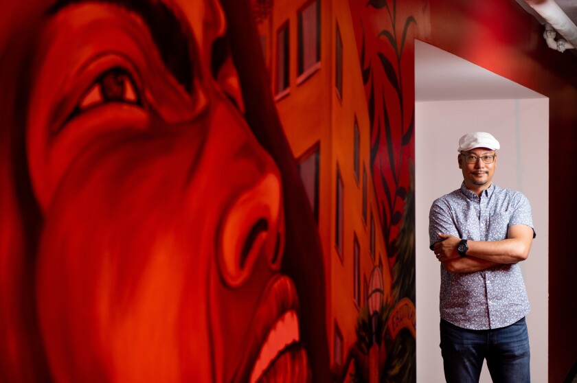 Jamil Wilson stands next to a red mural
