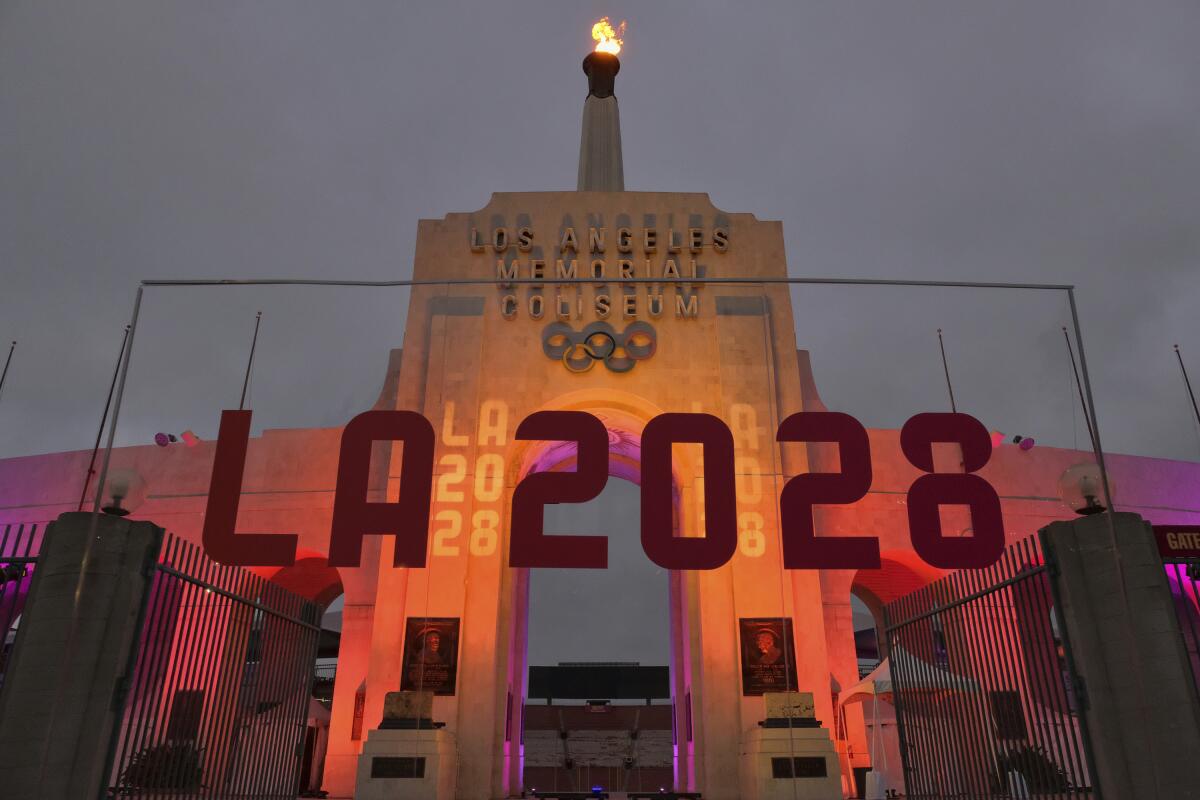 An LA 2028 sign in front of a blazing Olympic cauldron