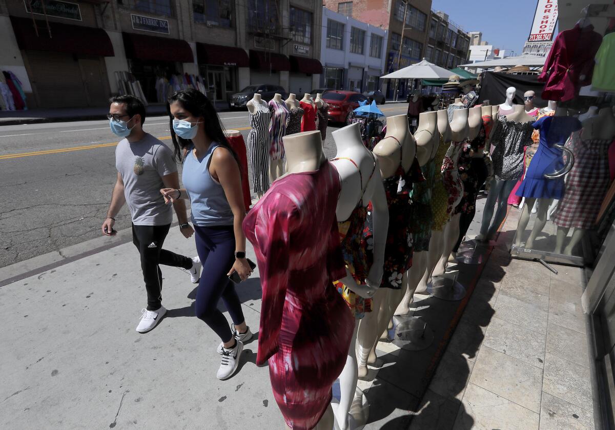 Shoppers wearing protective masks walk around the garment district on Thursday in downtown Los Angeles.