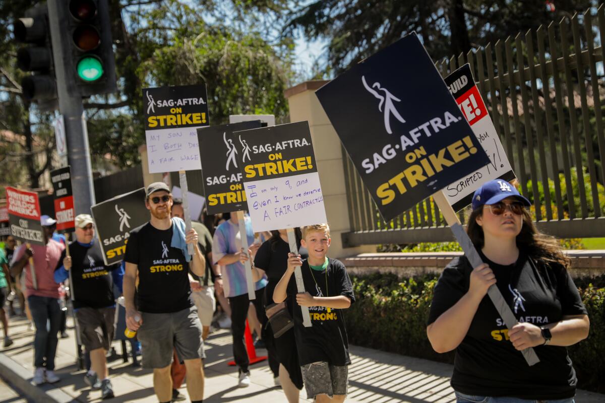 Actors carrying signs saying "SAG-AFTRA on Strike!" walk a picket line outside Warner Bros. studio in Burbank on July 14.
