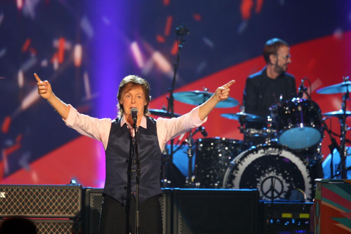 Paul McCartney, shown performing during a 50th anniversary Beatles television tribute, returns to tour after illness.
