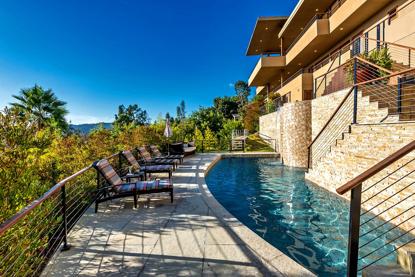 A deck with lounge chairs borders a narrow, rectangular pool.