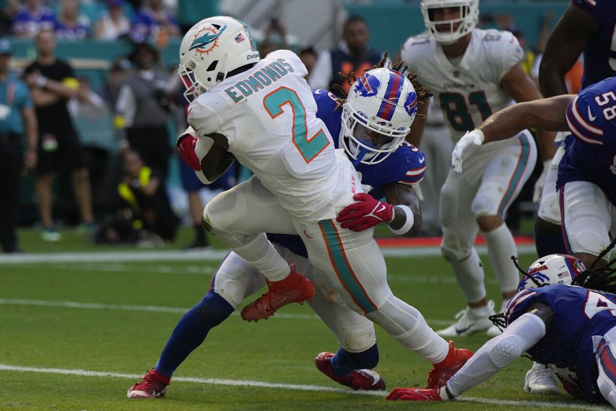 Chase Edmonds (2), corredor de Dolphins de Miami, anota un touchdown en contra de los Bills de Buffalo mientras el safety Damar Hamlin (3) intenta derribarlo para impedirlo, durante la segunda mitad del juego de la NFL, el domingo 25 de septiembre de 2022, en Miami Gardens, Fla. (AP Foto/Rebecca Blackwell)
