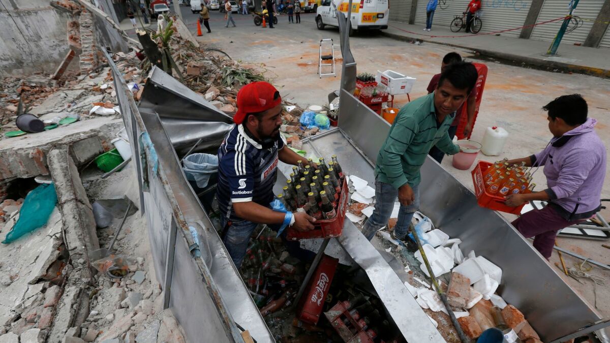 Workers salvage sodas from their damaged taco stand in Mexico City after an earthquake struck off the Pacific coast, hundreds of miles away.