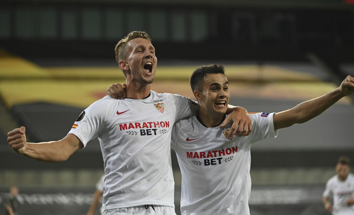 Sevilla's Luuk de Jong, left celebrates after scoring his sides 2nd goal of the game, with teammate Sevilla's Sergio Reguilon during the Europa League semifinal soccer match between Sevilla and Manchester United in Cologne, Germany, Sunday, Aug. 16, 2020. (Ina Fassbender/Pool Via AP)