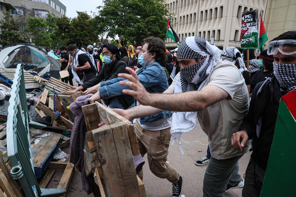 Protesters toss pallets and other debris to form a barrier between them and police on May 15 at UC Irvine. 
