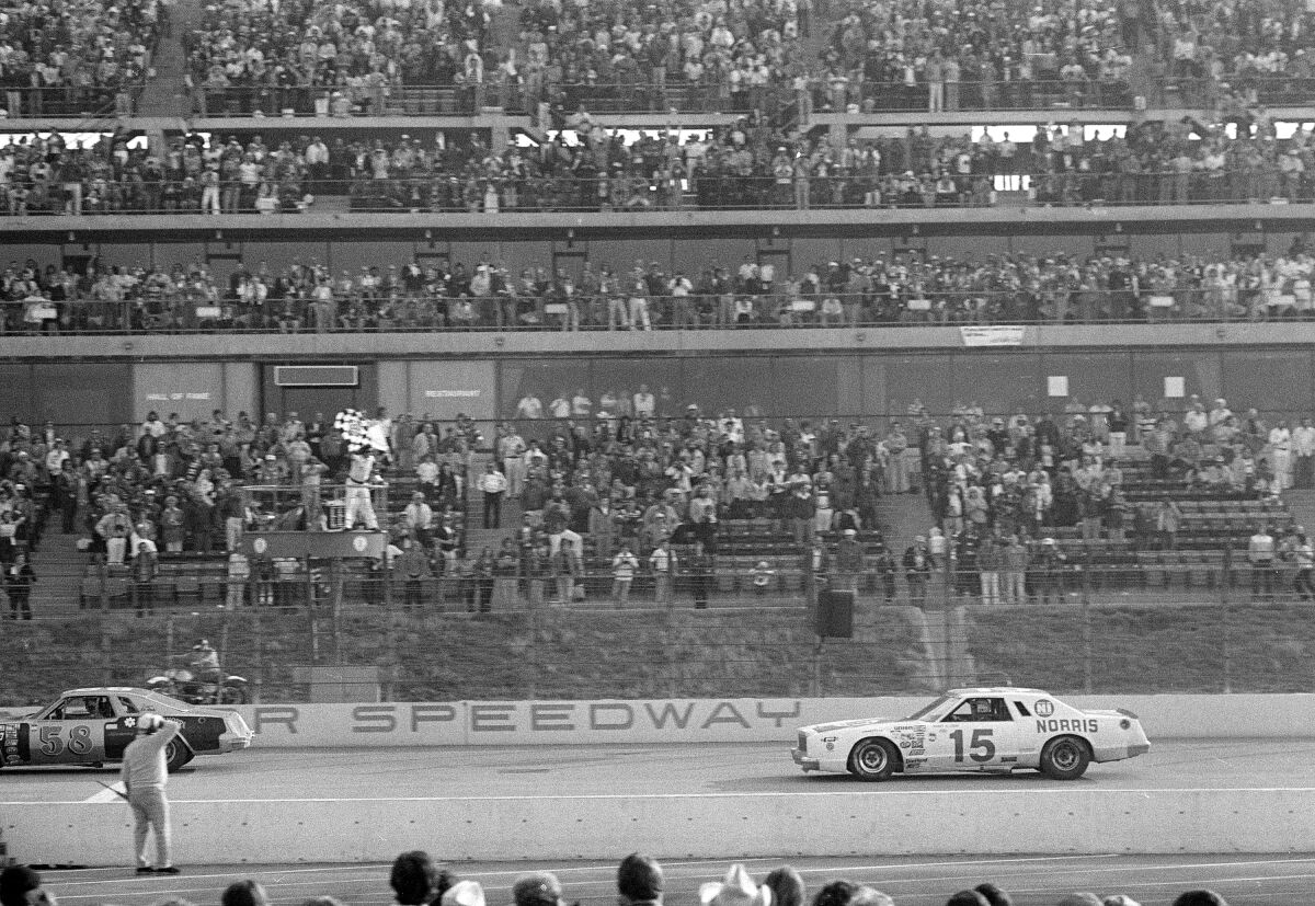 Bobby Allison prend le drapeau à damier alors qu'il franchit la ligne d'arrivée pour remporter le Times 500 à l'Ontario Motor Speedway.