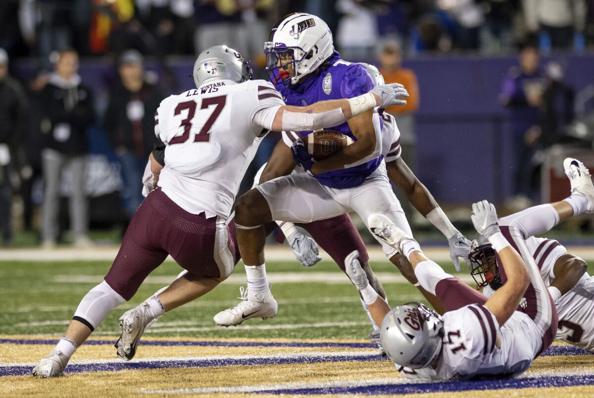 James Madison wide receiver Antwane Wells Jr. (7) picks his way through traffic as Montana linebacker Jace Lewis (37) closes in for the tackle during the first half of an NCAA FCS football playoff game in Harrisonburg, Va., Friday, Dec. 10, 2021. (Daniel Lin/Daily News-Record via AP)