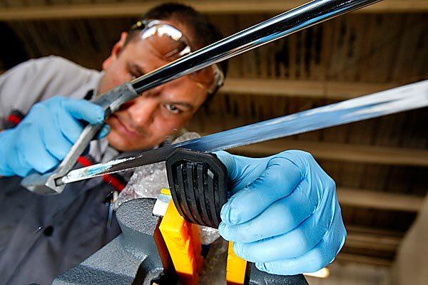 Toyota of Hollywood team leader Erick Garcia uses a hacksaw to shorten the gas pedal as part of the fix for several models that Toyota has recalled because of reported problems with the gas pedal sticking.