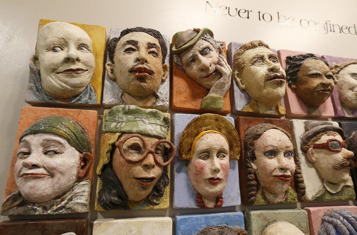 Guests look over the ceramic faces of artist Paula Collins' expansive piece "Zoomland" at the Festival of Arts show.