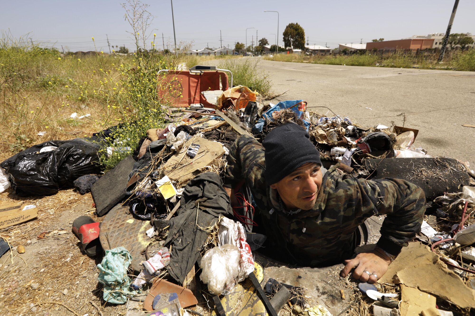 Juan Luis Gonzalez-Castillo climbs out of a storm drain where he lived in a vacant field in Watts. 