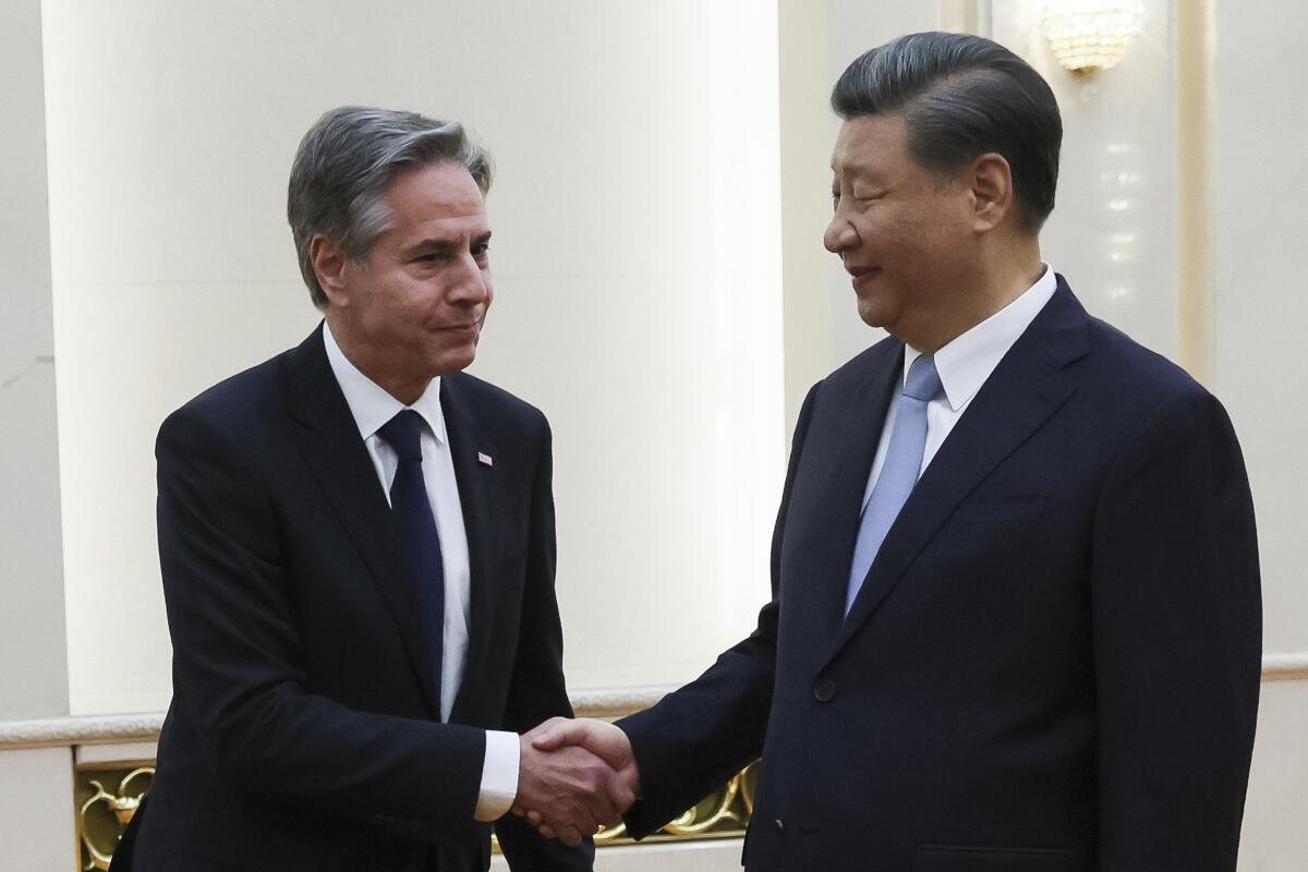 Antony J. Blinken and Xi Jinping standing and shaking hands.