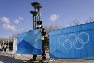 A worker erects barriers outside the Main Media Center at the 2022 Winter Olympics, Jan. 31, 2022, in Beijing. (AP Photo/Matt Slocum)