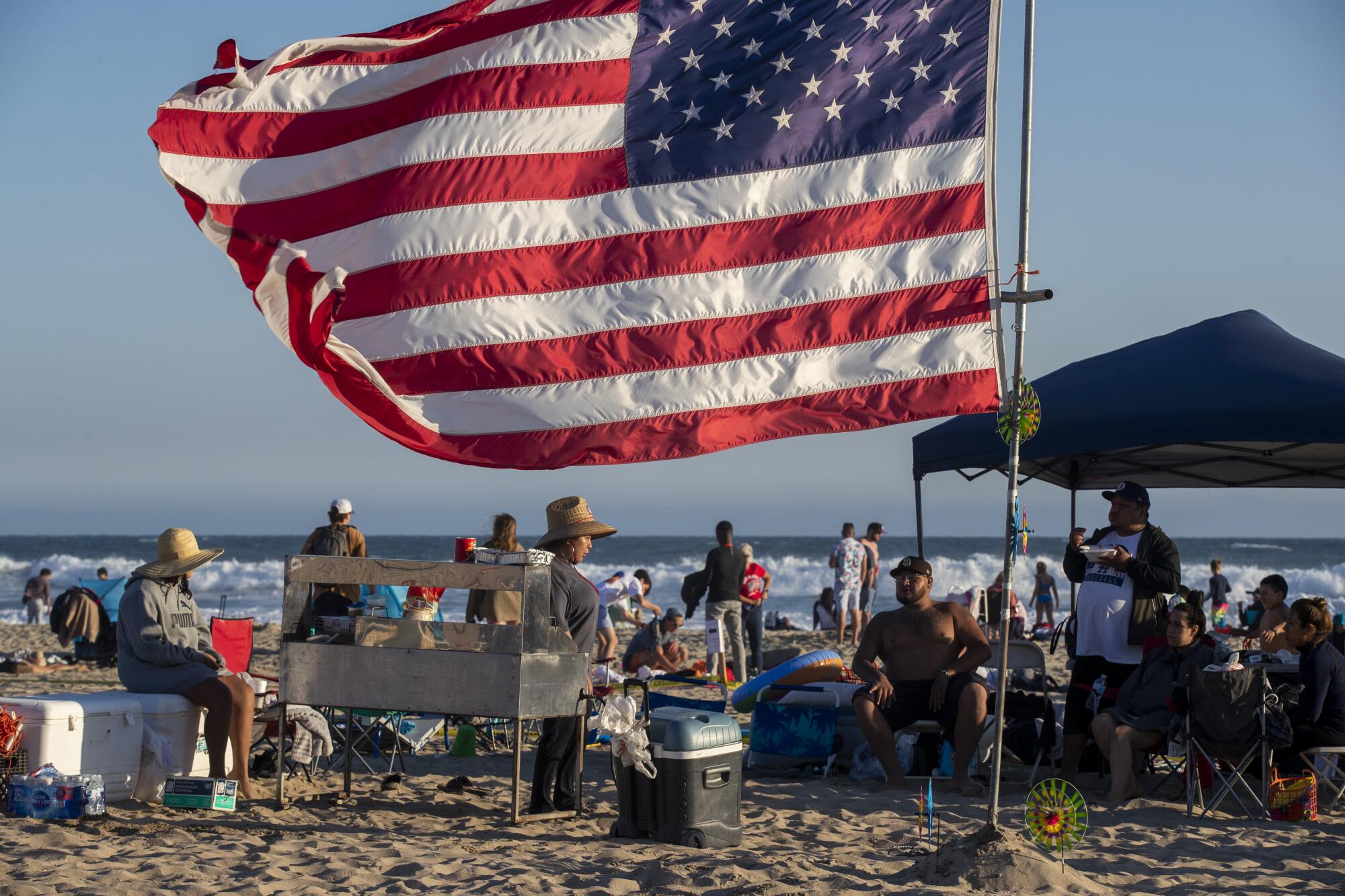 A big U.S. flag flies near a gathering on the beach