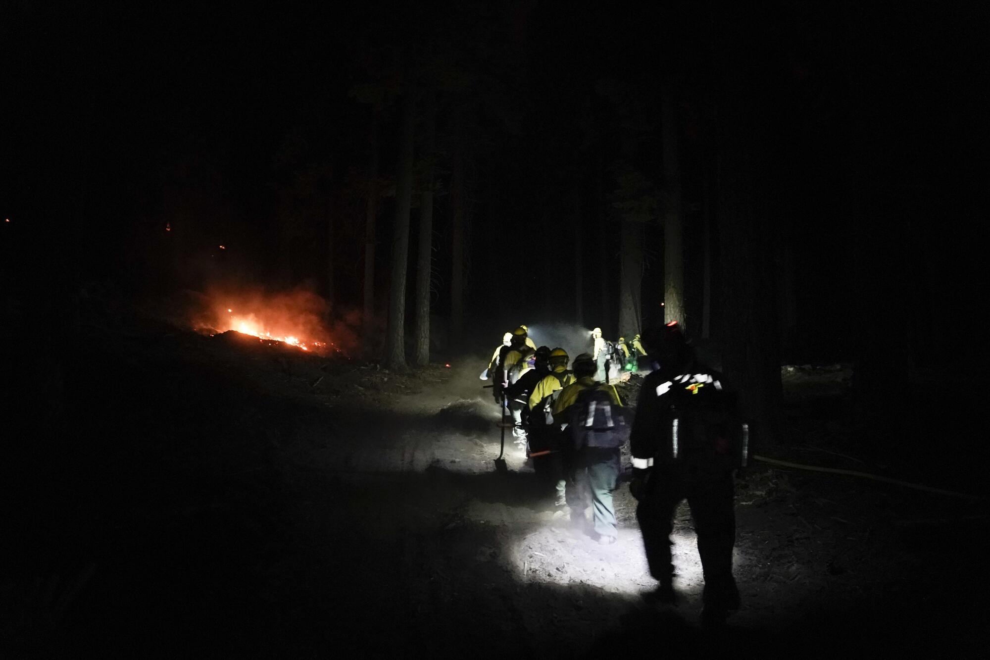 Firefighters battling the Caldor fire walk toward flames near South Lake Tahoe on Monday.