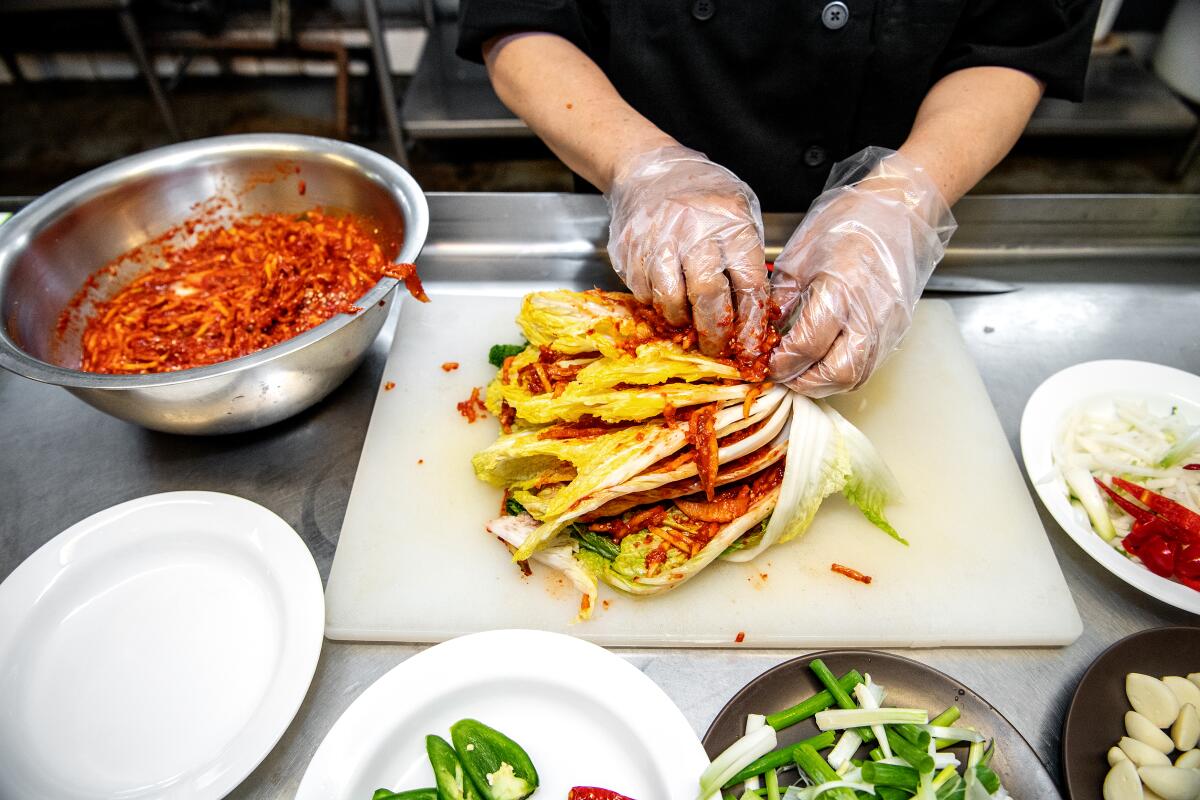 Kyungsook Oh applies sok in between the leaves of a napa cabbage.