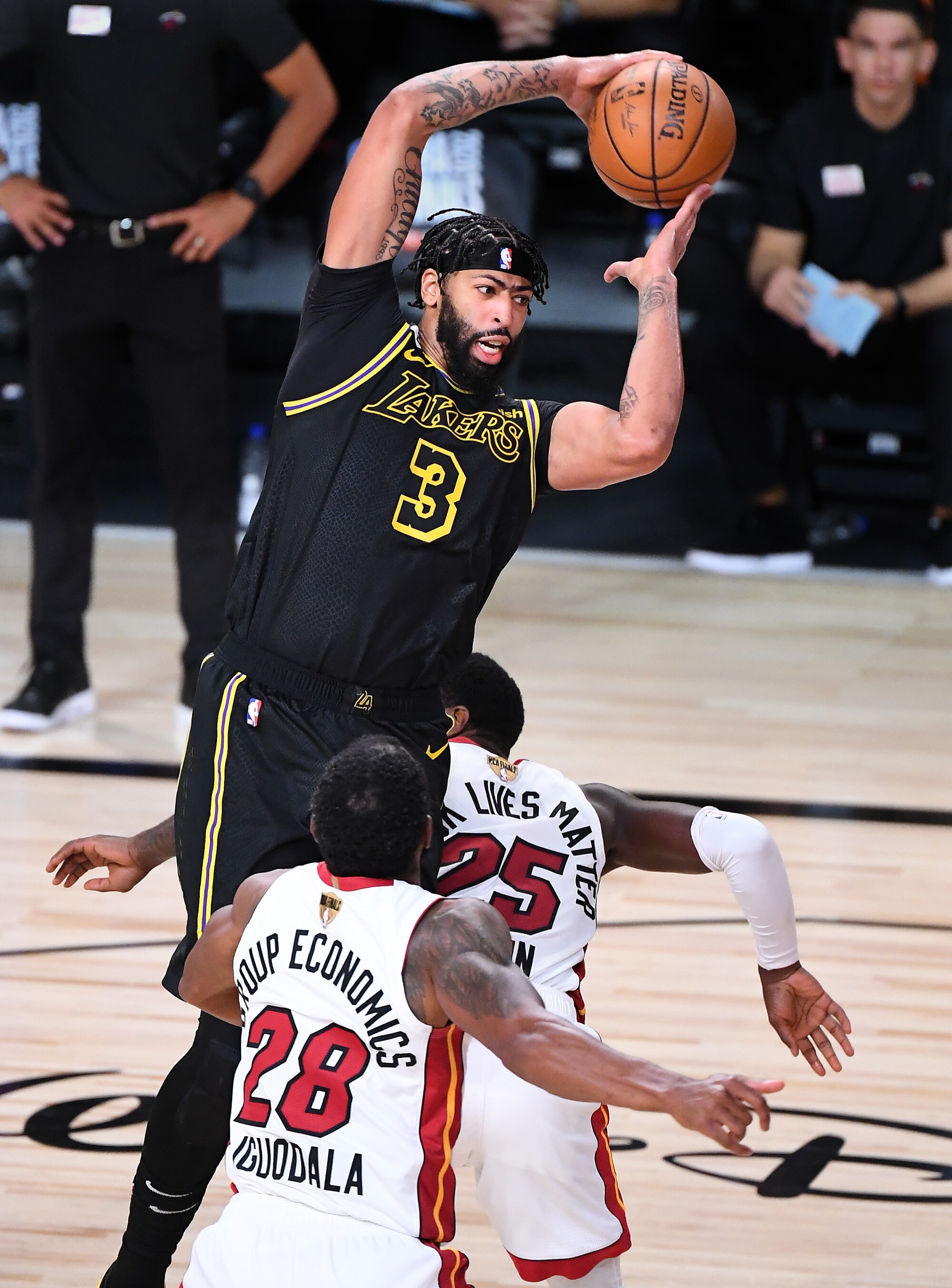Lakers forward Anthony Davis grabs a rebound over Miami's Andre Iguodala and Kendrick Nunn.
