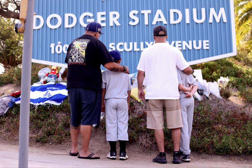 LOS ANGELES CA AUGUST 2, 2022 - Fans pay their respects at a growing memorial outside Dodger Stadium for legendary Los Angeles Dodgers broadcaster Vin Scully Wednesday morning, August 3, 2022, after hearing of his passing at the age of 94. (Wesley Lapointe / Los Angeles Times)