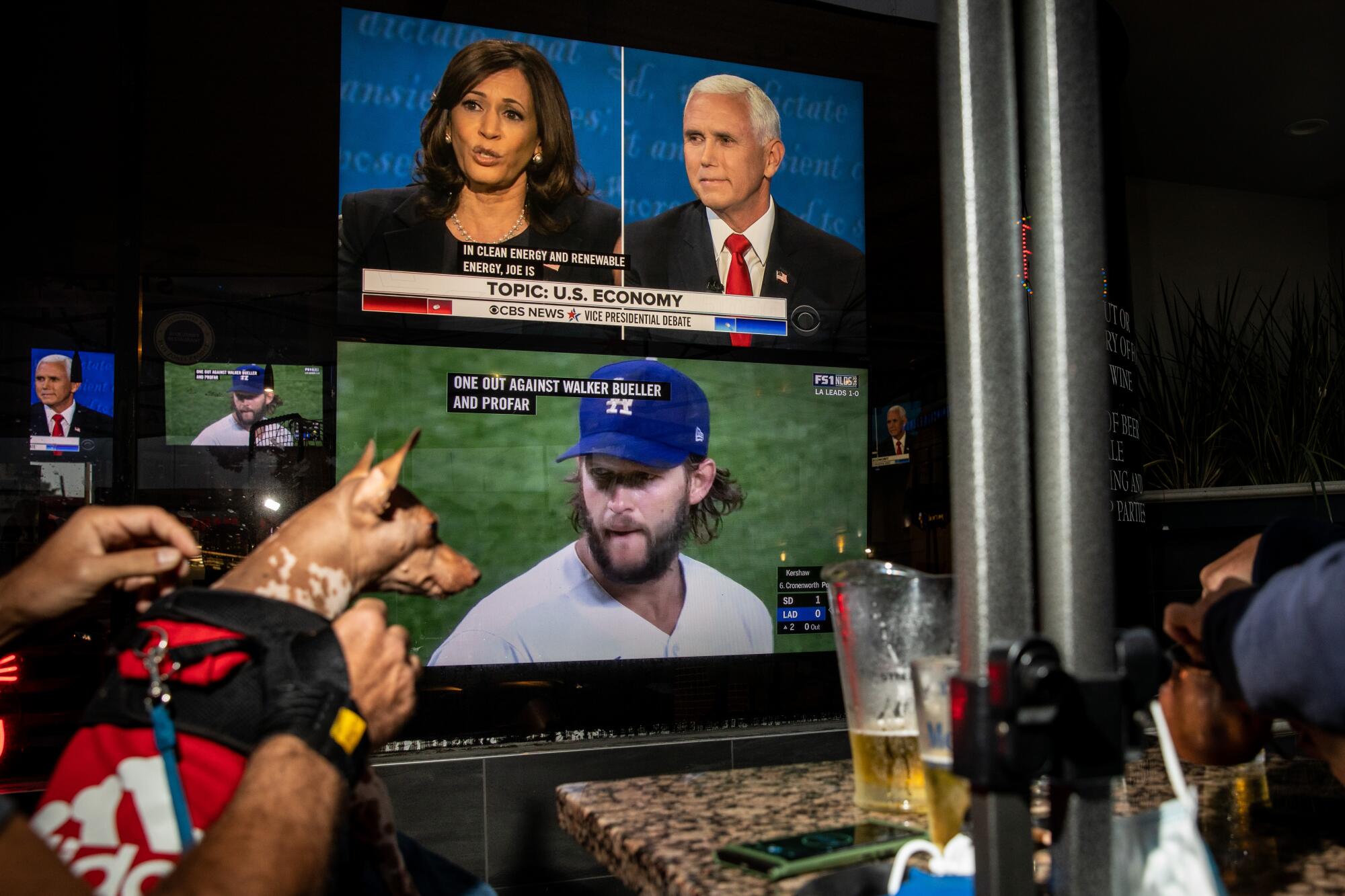 TV screens at a bar show the vice presidential debate and the Dodgers playoff game