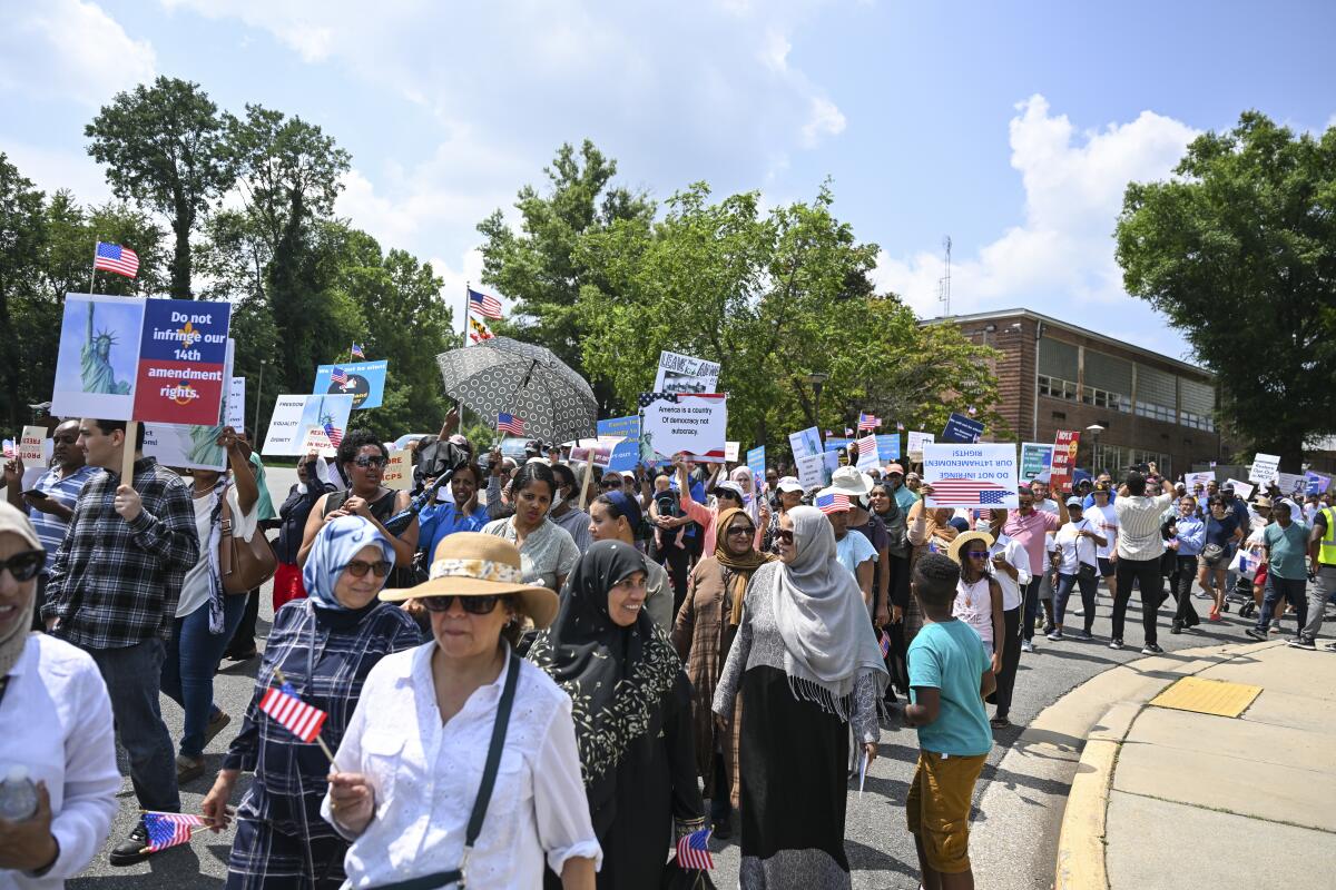 People rally and hold signs outside a school board building.