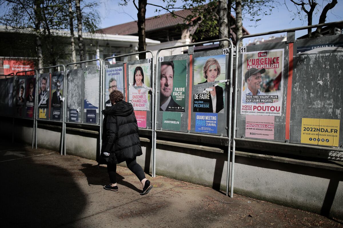 A woman walks past presidential campaign posters