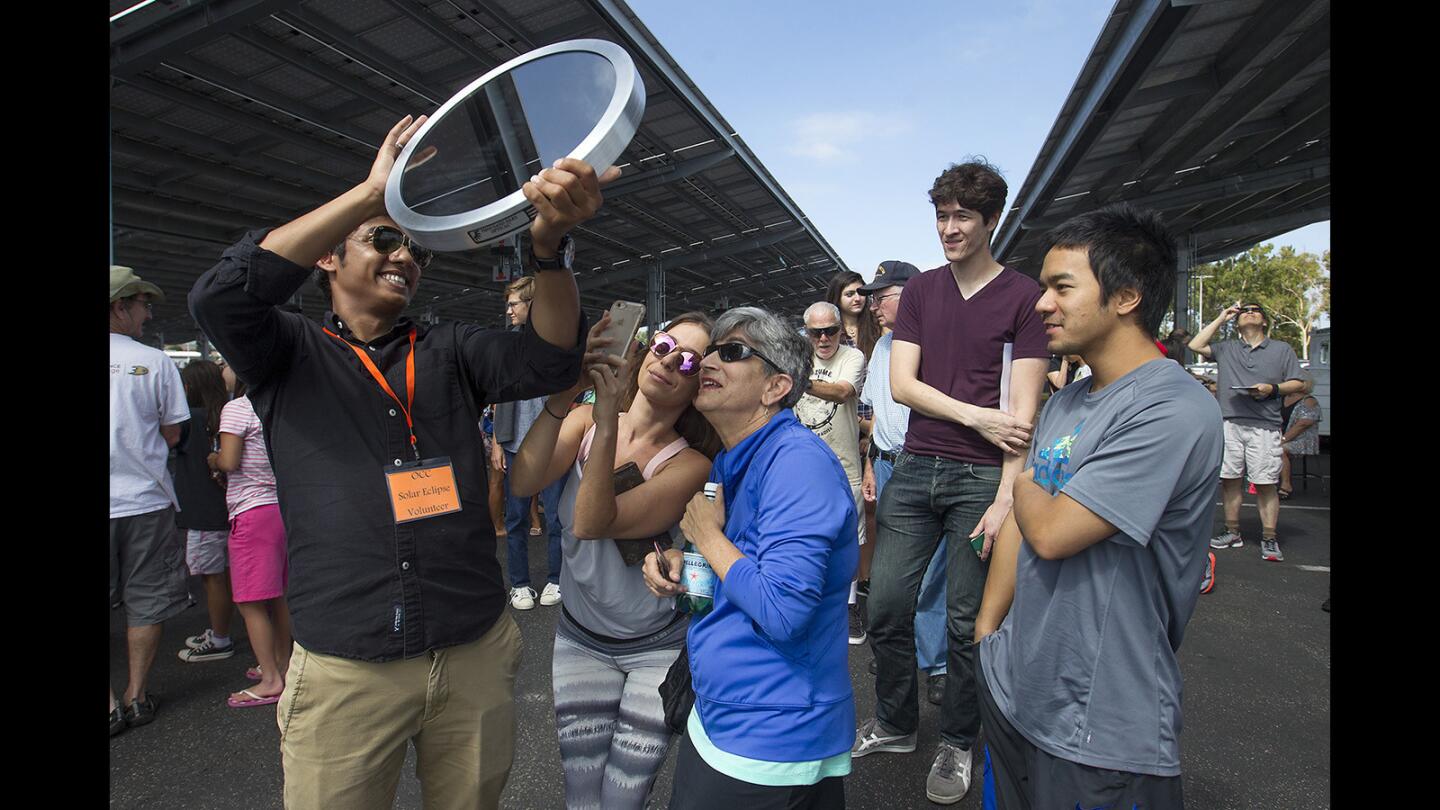 OCC solar eclipse volunteer Azzam Alhejaili holds a two-way solar mirror up to the sun for visitors to view the solar eclipse during the OCC Astronomy Department's solar eclipse viewing event on Monday.