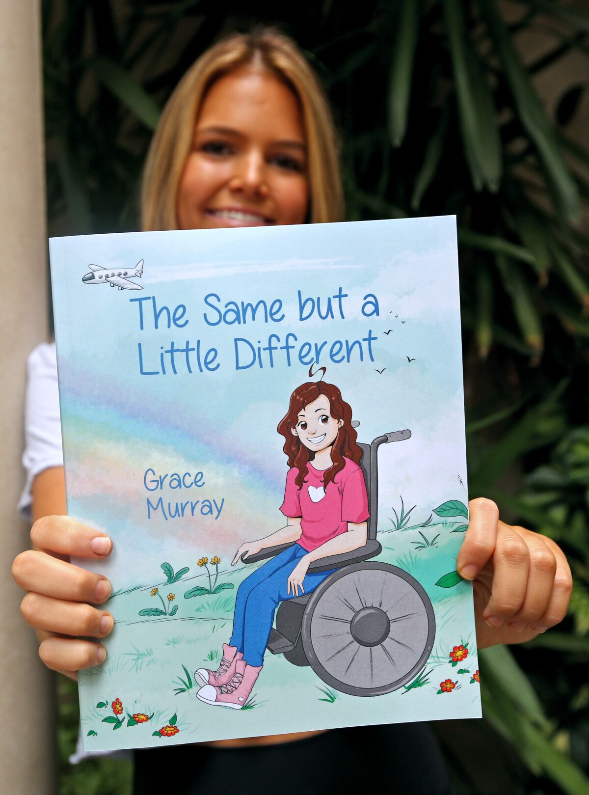 Grace Murray shows off the cover of "The Same But A Little Different" book she self-published.