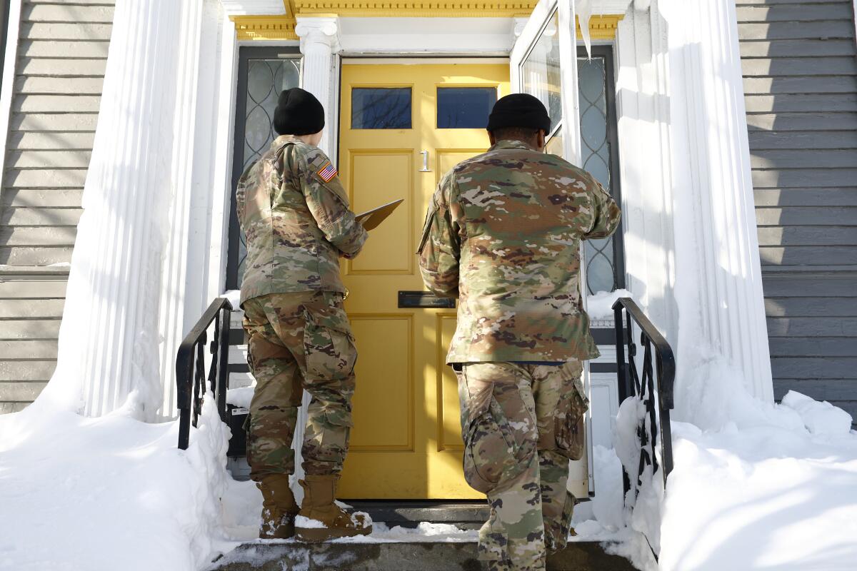 Two National Guard members at a home's front door.