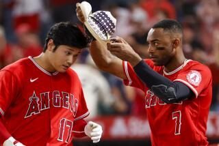 Los Angeles Angels' Jo Adell (7) puts a cowboy hat onto Shohei Ohtani (17) while celebrating.