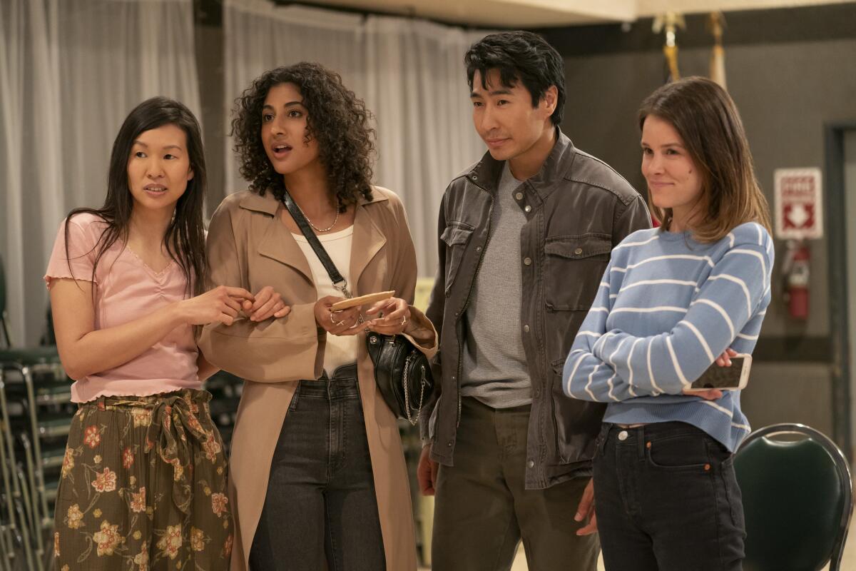 Three women and a man, clustered together, watching something out of frame