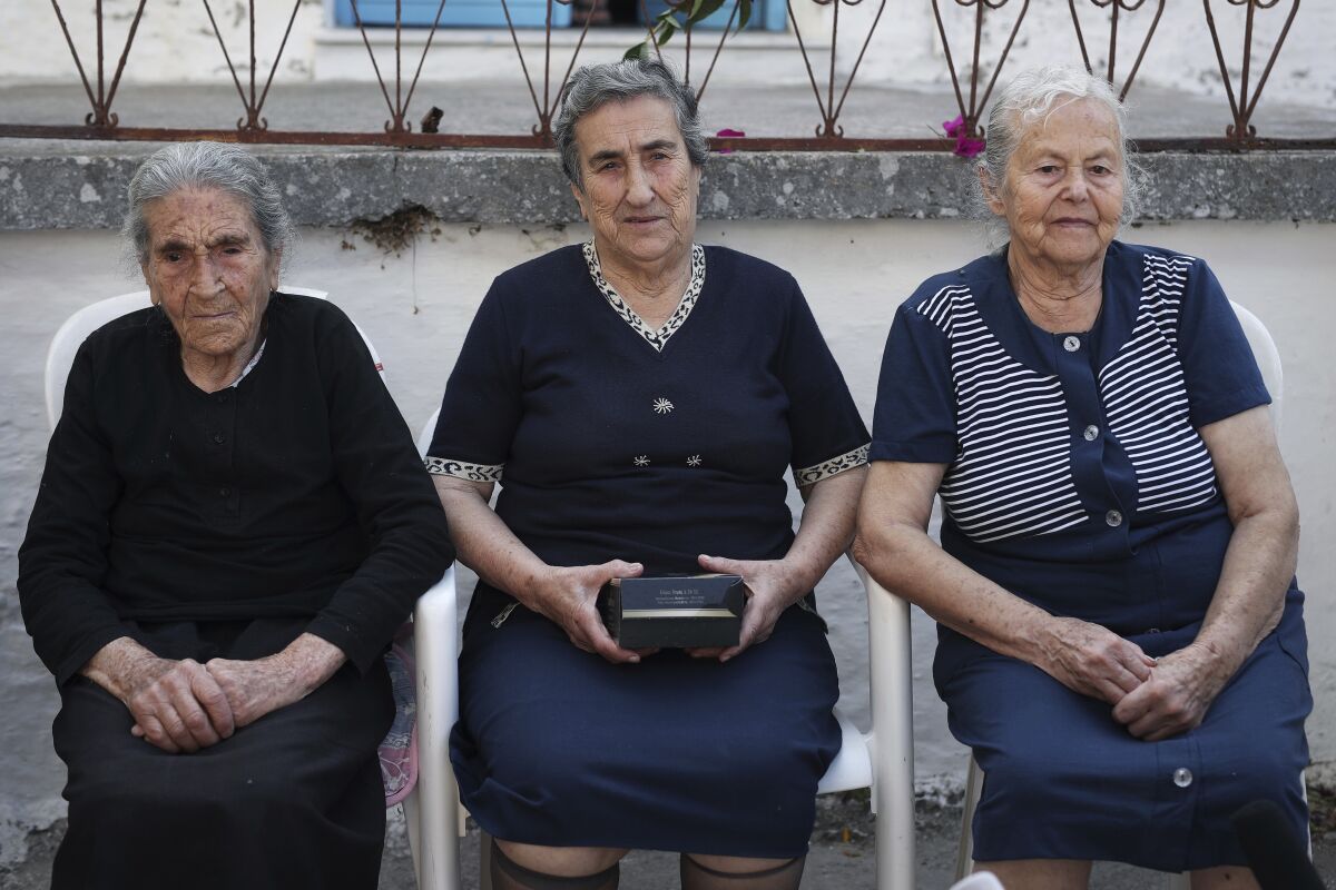 FILE - Emilia Kamvisi, center, a co-nominee for the Nobel Peace Prize, sits with her friends Efstratia Mavrapidou, left, and Maritsa Mavrapidi, in the village of Skala Sikaminias, on the northeastern Aegean island of Lesbos, Greece, on Oct. 7, 2016. Efstratia Mavrapidou, one of three elderly Greek ladies who gained international renown at the height of Europe's migration crisis for helping refugees on her home island of Lesbos, has died on Tuesday, Feb. 15, 2022. She was 96. (AP Photo/Petros Giannakouris, File)