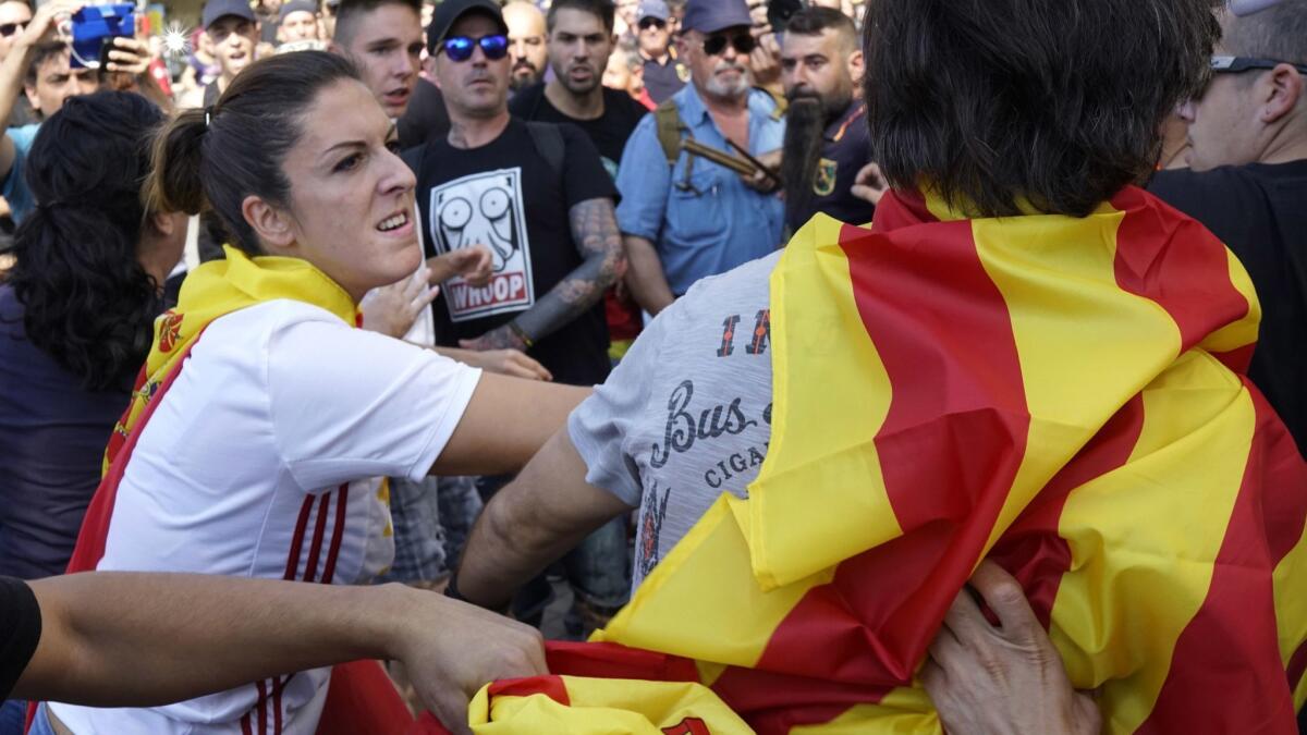 A woman wearing a Spanish flag hits a man wearing an Independence flag, following a demonstration erupting in clashes in Barcelona, Spain, on Saturday.