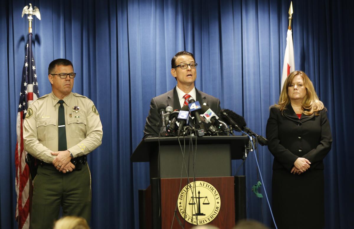 A district attorney speaks at a lectern with microphones on it