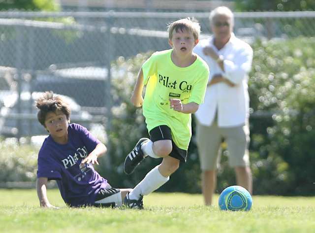 A Whittier 5th grader tries to slide tackle a Mariners ball handler, right, as the two play in boys 5-6 gold championship game Sunday.