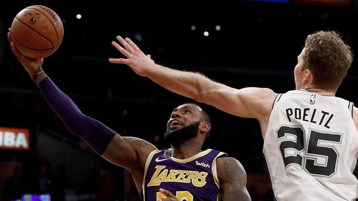 Lakers forward LeBron James spins and scores against Spurs' Jakob Poeltl in the fourth quarter.