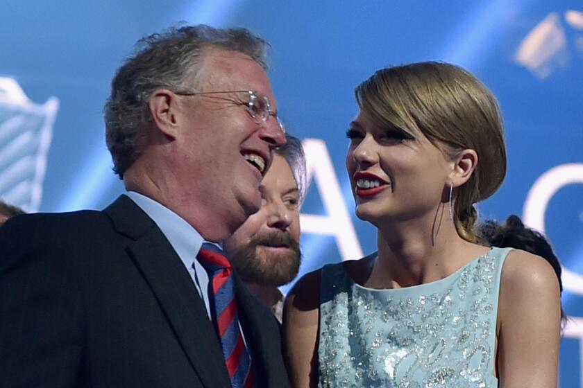 Scott Swift and his daughter Taylor Swift wear formalwear while smiling at each other onstage