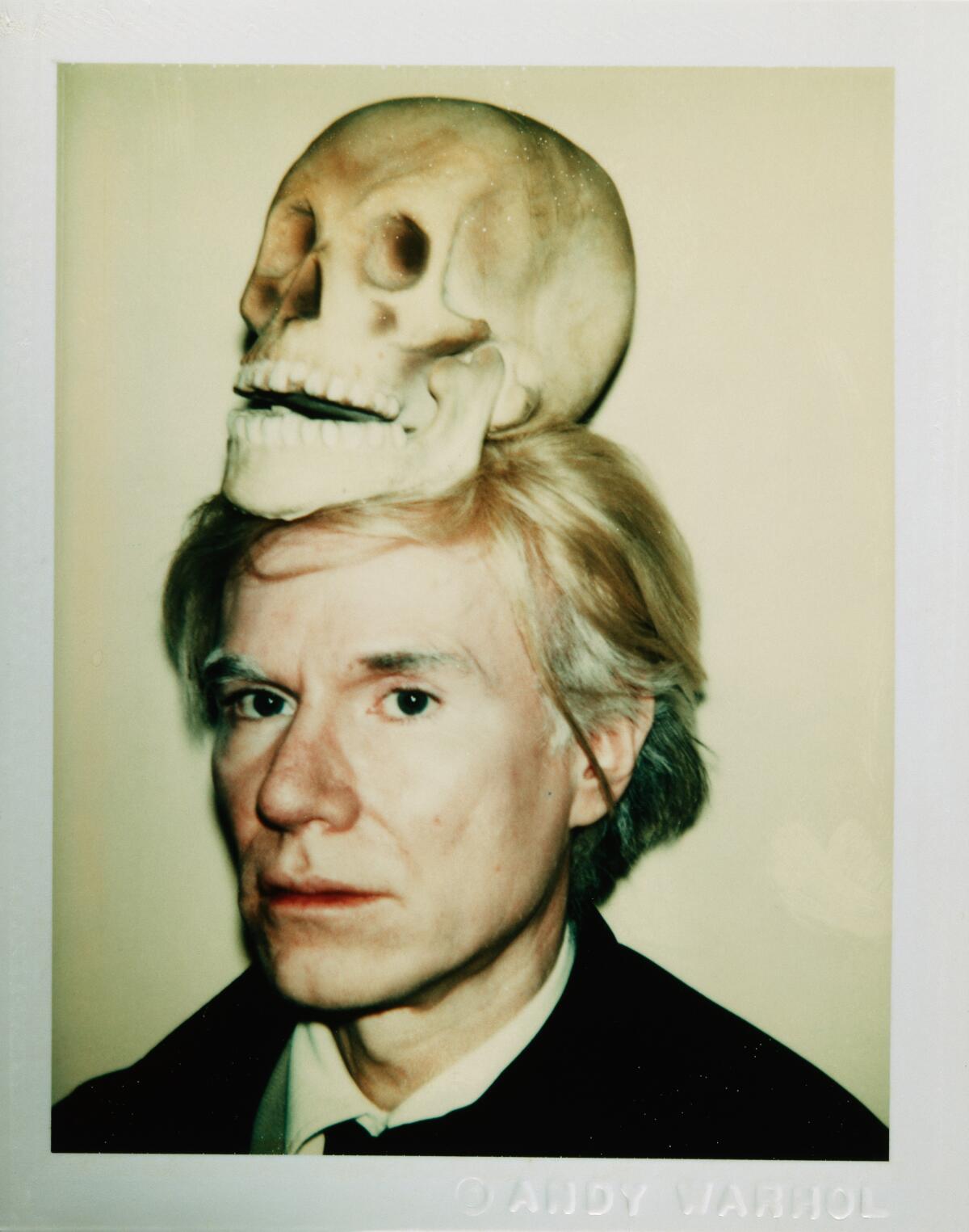 Andy Warhol pictured in a self portrait, with a skull on his head. 