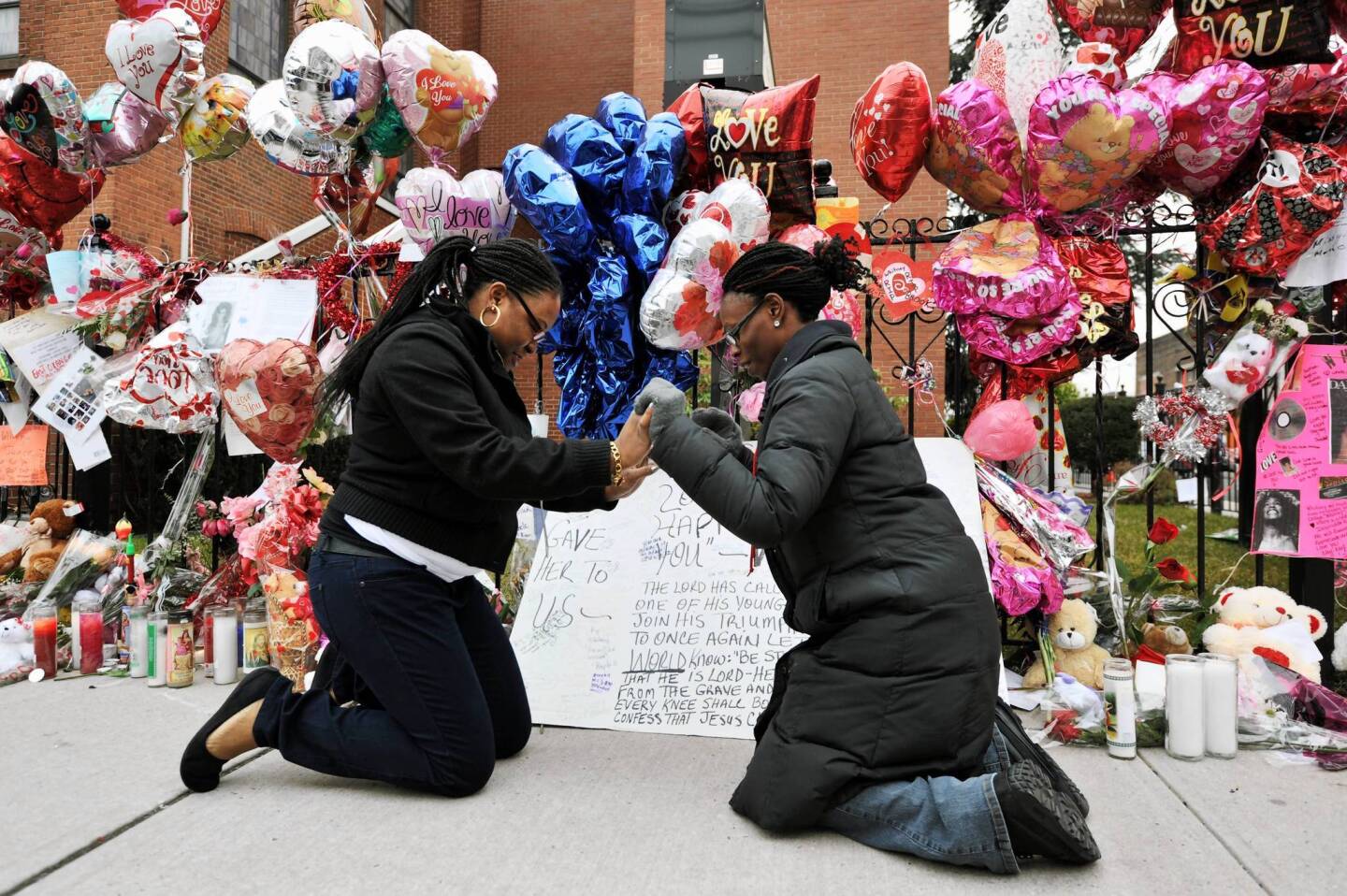 Amanda Kweku, left, and Latisha Watkins, right, pray in front of a display of messages for singer Whitney Houston at the New Hope Baptist Church in Newark, New Jersey.