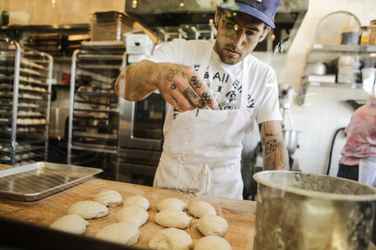 Alex Phaneuf, co-owner and baker of Lodge Bread in Culver City, preps shaped dough, sprinkling salt on top.